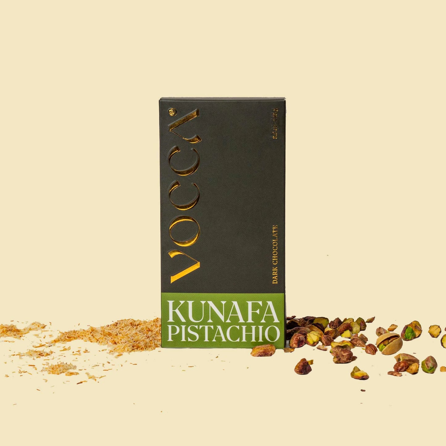 Vocca Kunafa Pistachio chocolate bar packaging on a beige background with pistachios.